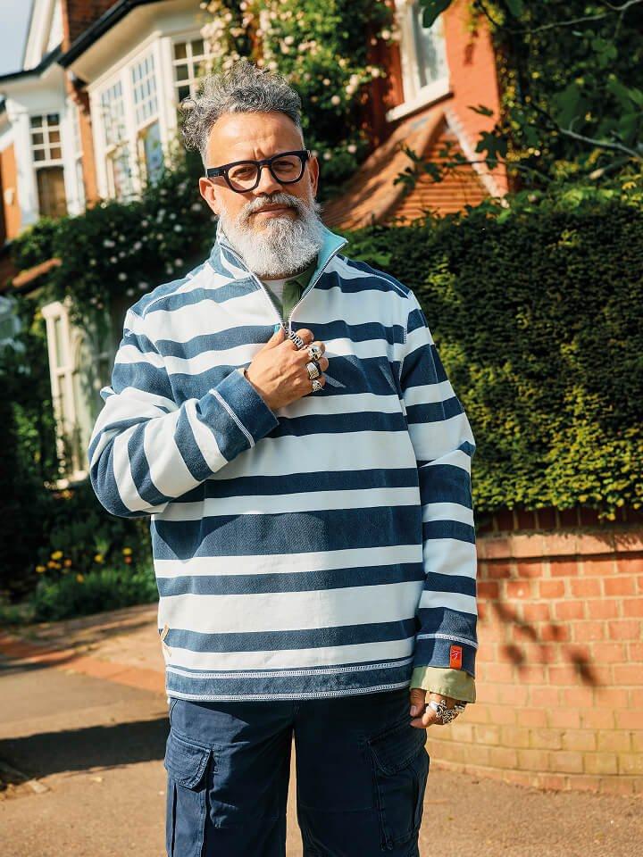 a man with a beard and glasses standing in front of a house